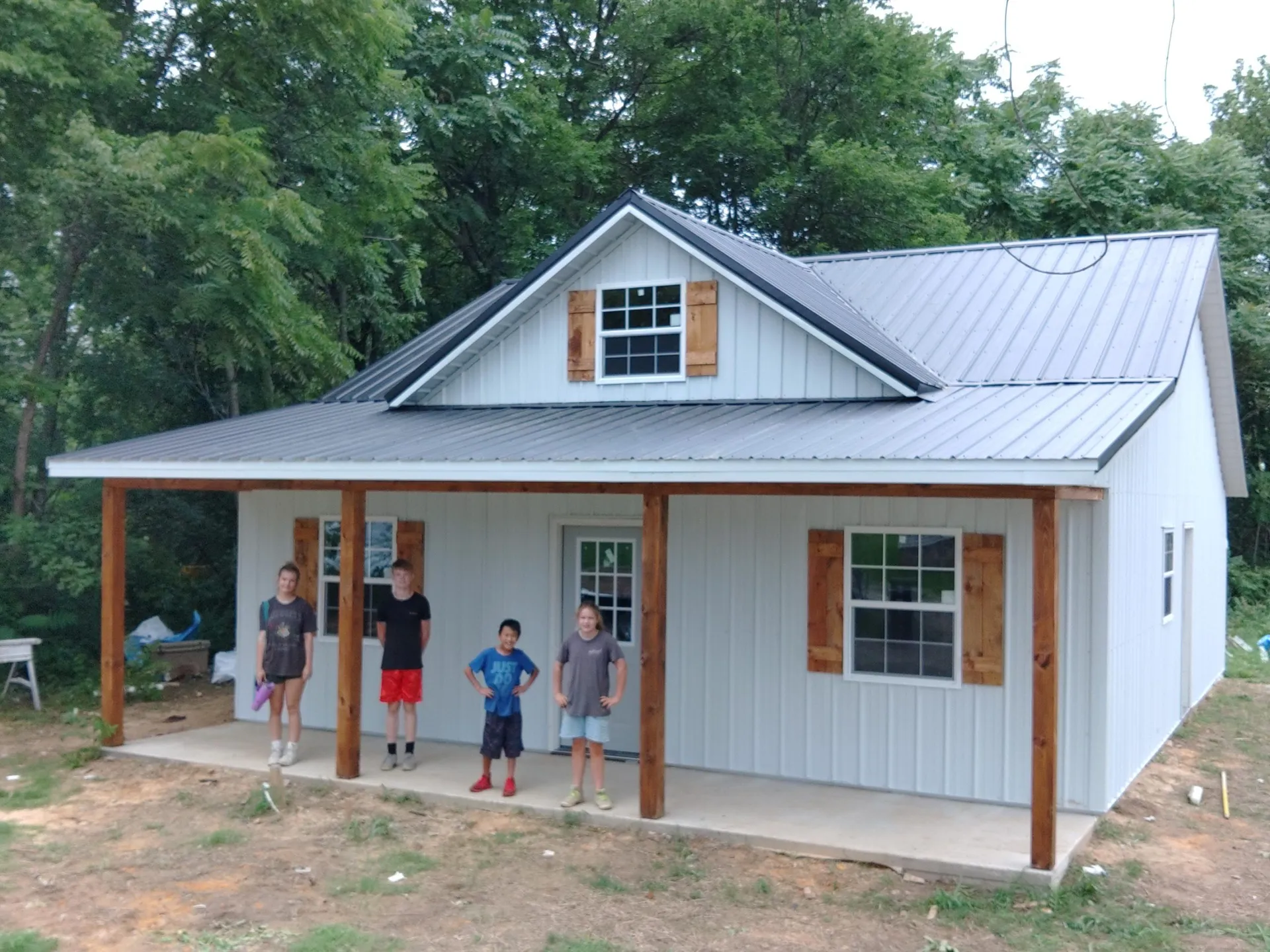 Finished white wood-framed house kit with metal roof and covered porch